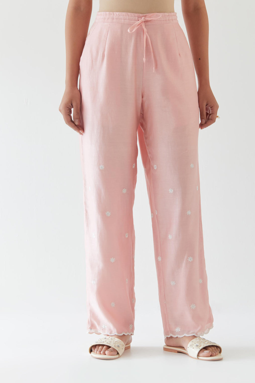 Pink silk chanderi straight pants with off white thread embroidery and scalloped edges at hem.