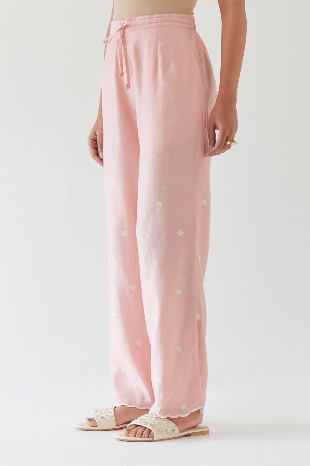 Pink silk chanderi straight pants with off white thread embroidery and scalloped edges at hem.