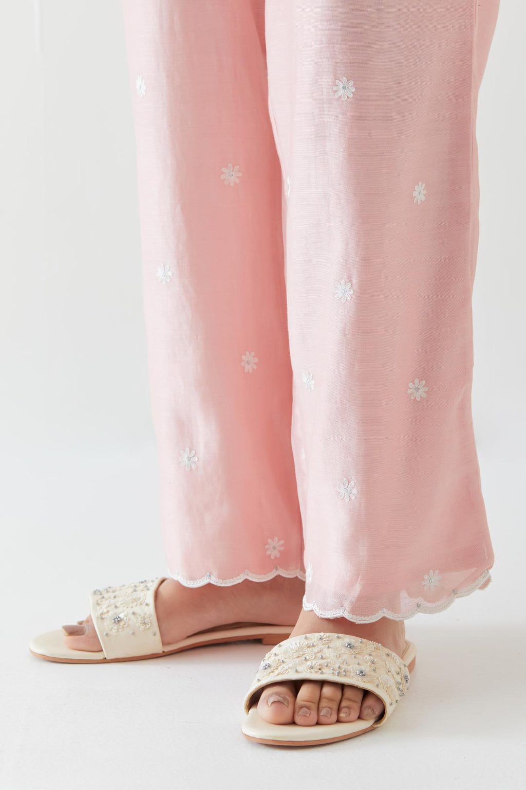 Pink silk chanderi straight pants with off white thread embroidery and scalloped edges at hem.