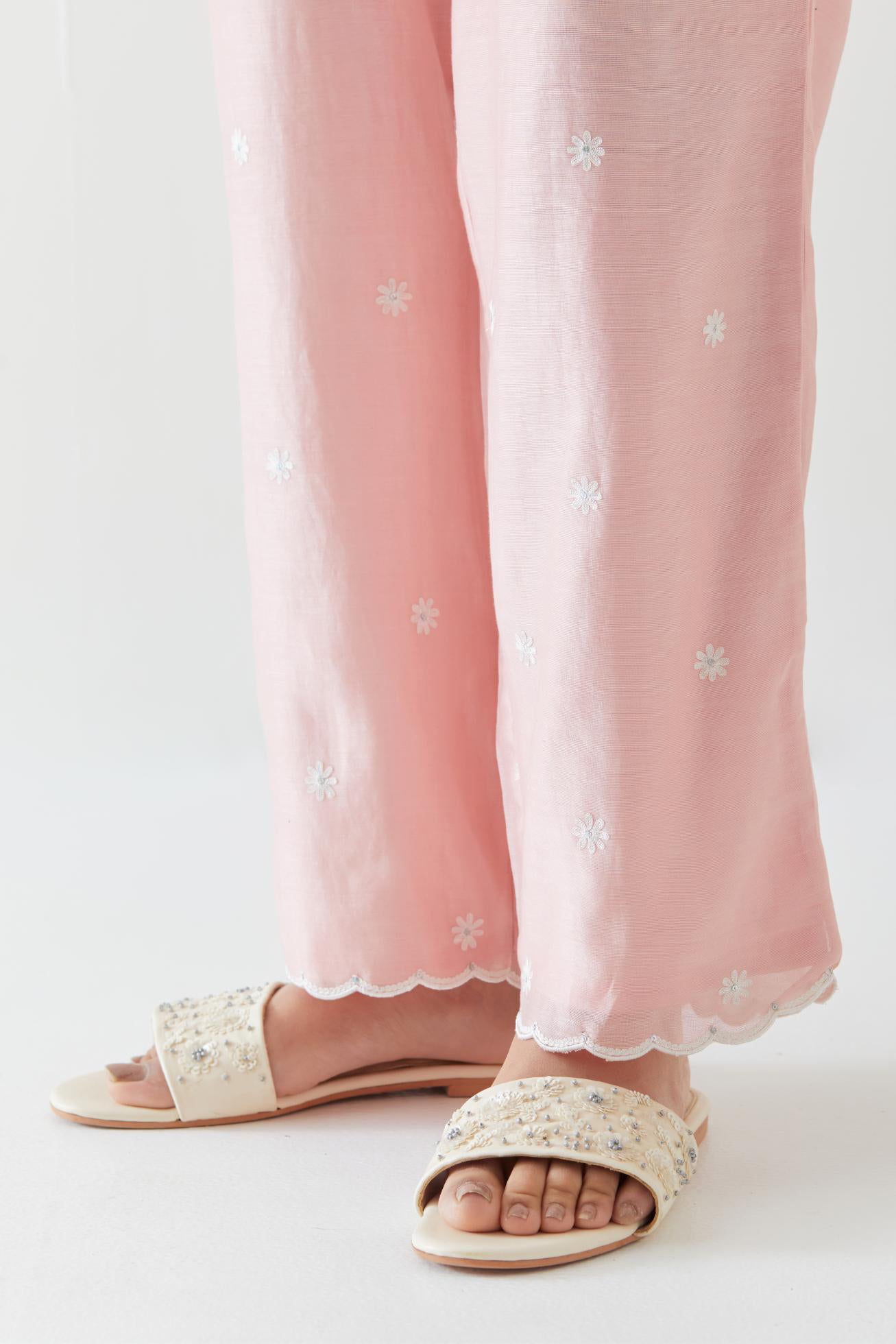 Pink silk chanderi straight pants with off white thread embroidery and scalloped edges at hem.