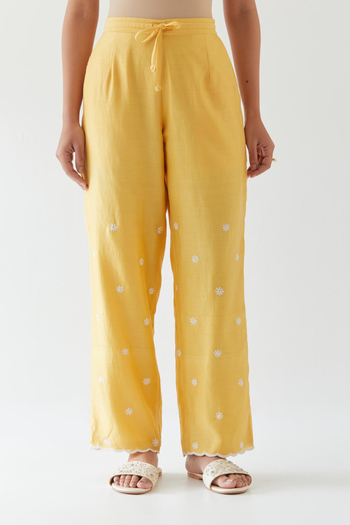 Yellow silk chanderi straight pants with off white thread embroidery and scalloped edges at hem.