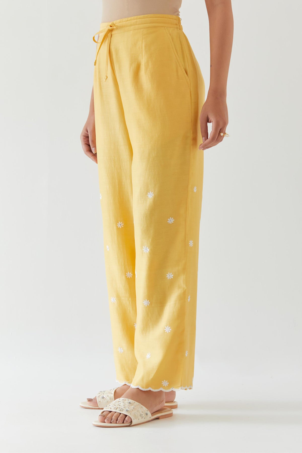 Yellow silk chanderi straight pants with off white thread embroidery and scalloped edges at hem.