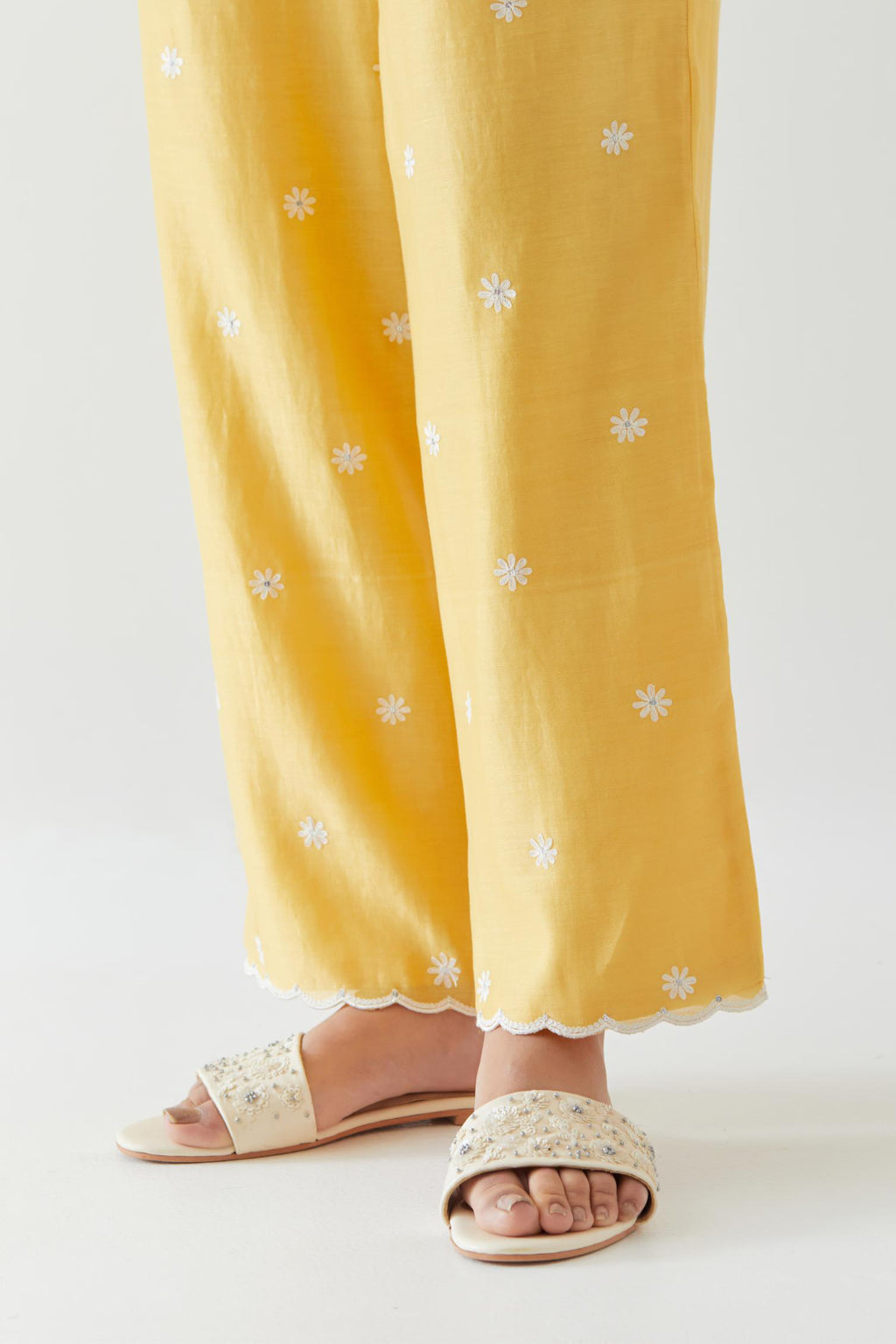 Yellow silk chanderi straight pants with off white thread embroidery and scalloped edges at hem.
