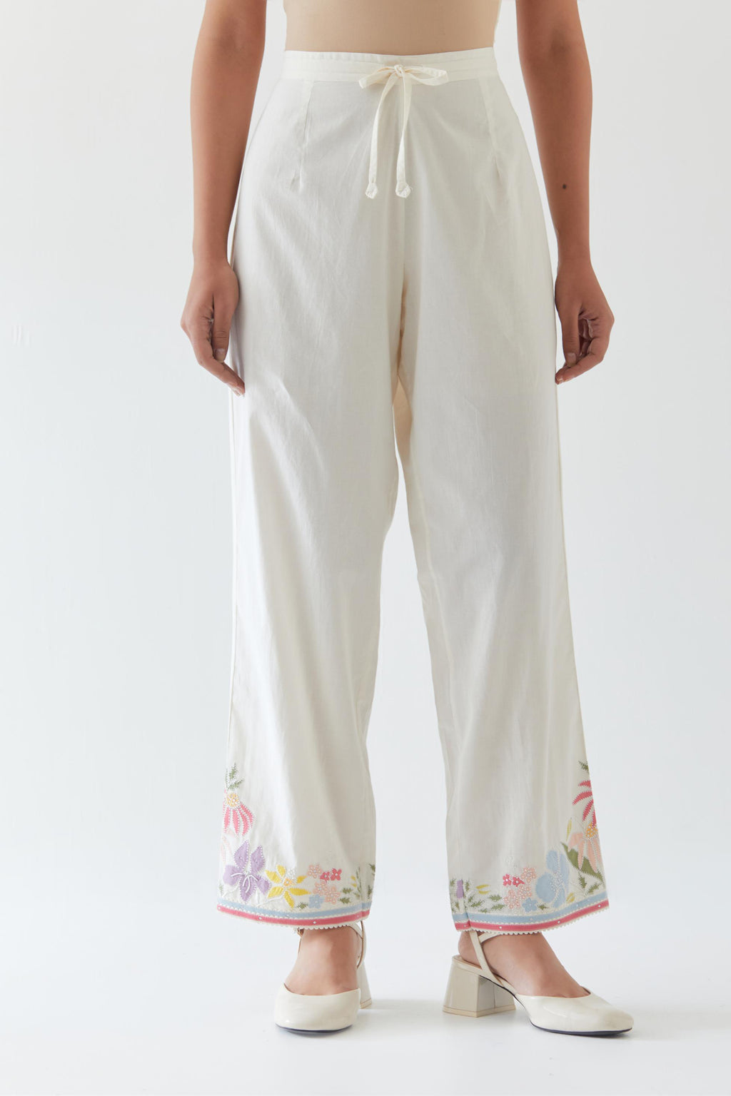Off white cotton straight pants detailed with multi colored applique, highlighted with bead & sequins work.
