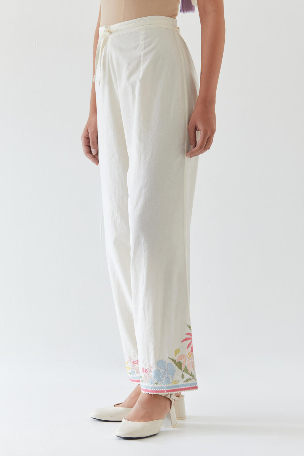 Off white cotton straight pants detailed with multi colored applique, highlighted with bead & sequins work.