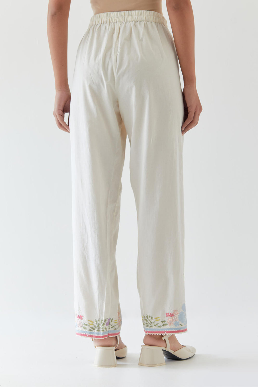 Off white cotton straight pants detailed with multi colored applique, highlighted with bead & sequins work.
