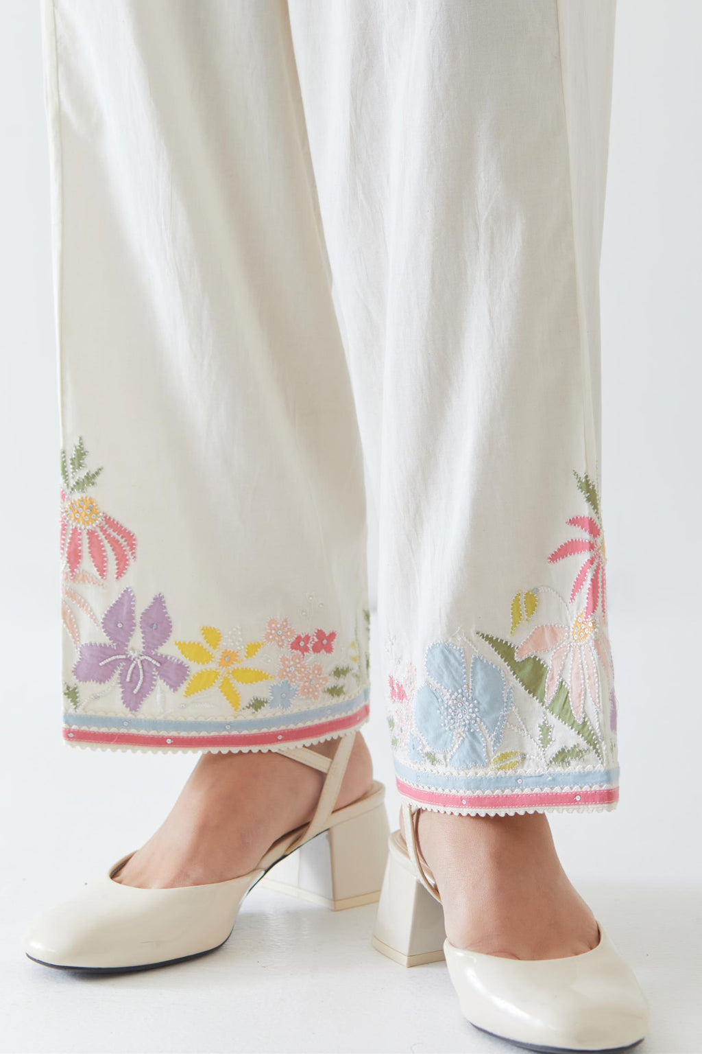 Off white cotton straight pants detailed with multi colored applique, highlighted with bead & sequins work.