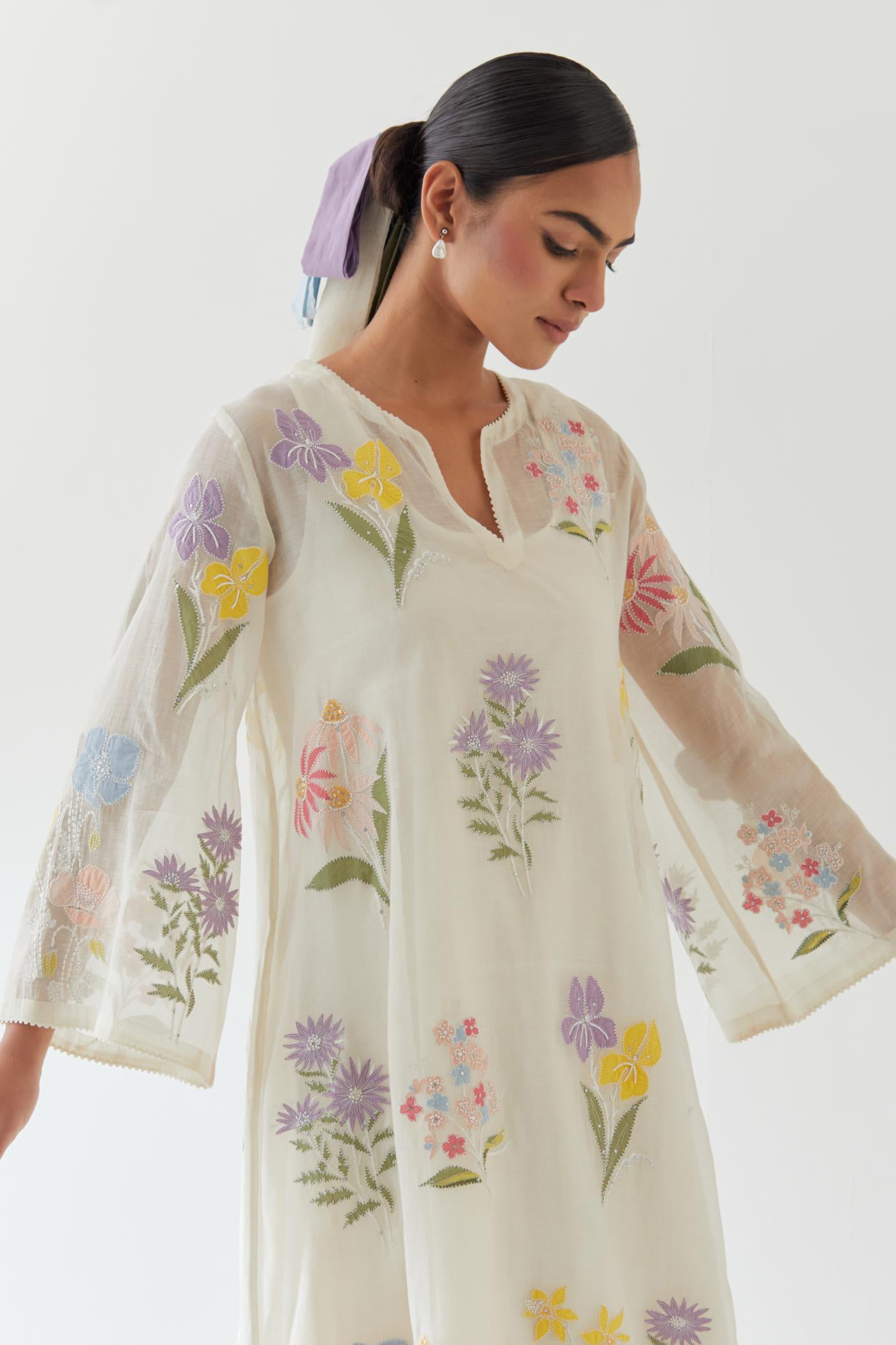 Off white cotton chanderi A-line kurta set features an all-over multi-colored assorted flower applique, highlighted with bead and sequins work.
