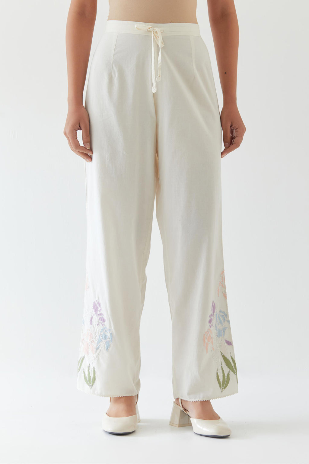Off white cotton straight pants detailed with multi colored applique, highlighted with bead & sequins work.