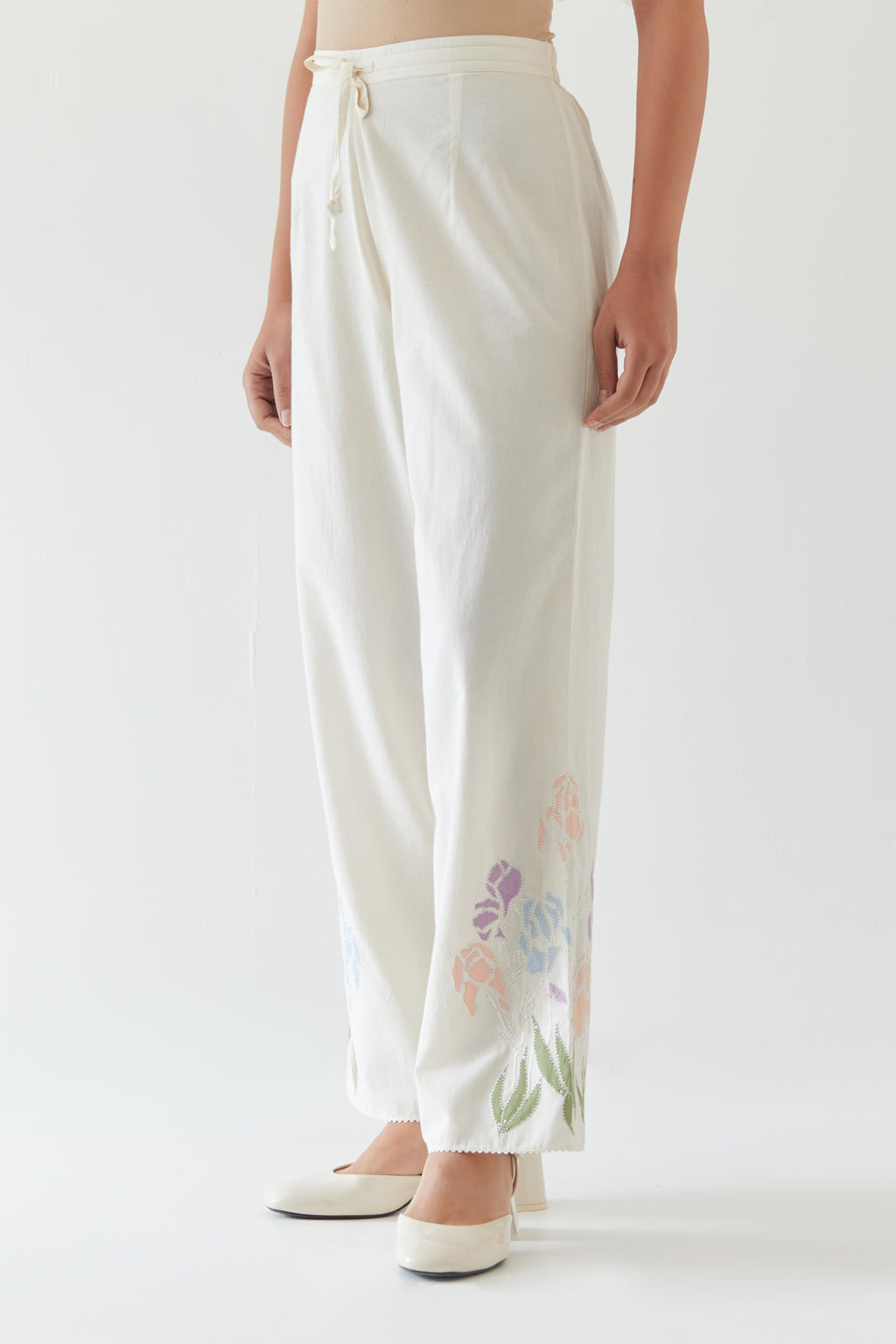 Off white cotton straight pants detailed with multi colored applique, highlighted with bead & sequins work.