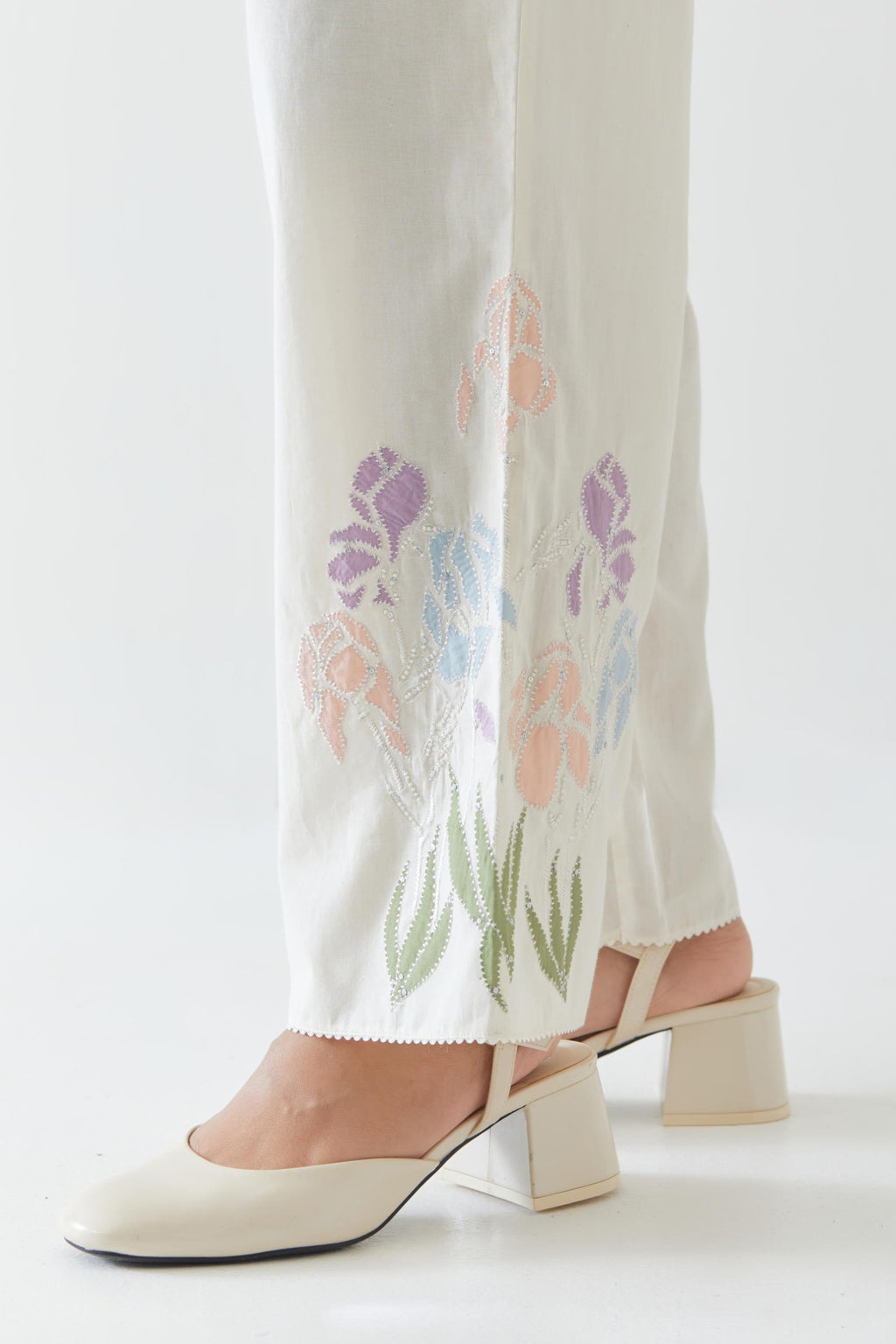 Off white cotton straight pants detailed with multi colored applique, highlighted with bead & sequins work.
