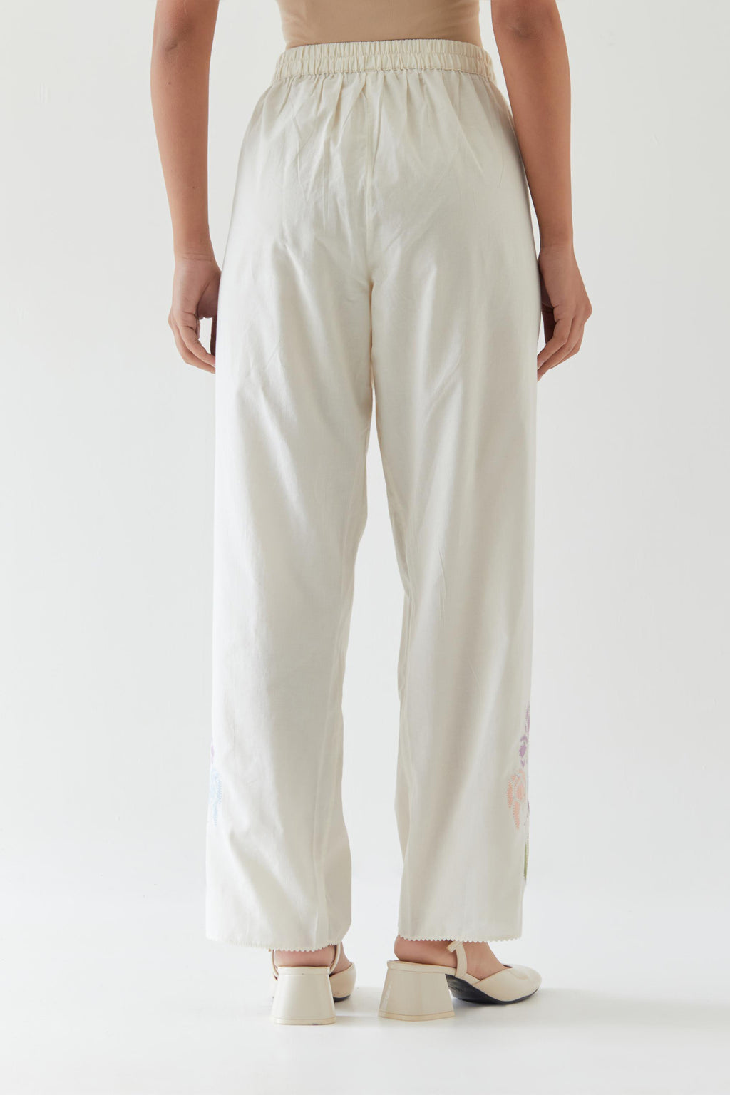Off white cotton straight pants detailed with multi colored applique, highlighted with bead & sequins work.
