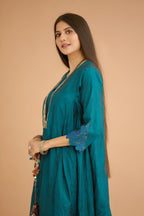 Teal green hand crushed silk kurta with cutwork embroidered asymmetric hem, highlighted with hand attached mirrors, paired with blue hand crushed silk pants with hand block print fine stripes and organza fabric and embroidery detail at bottom hem.