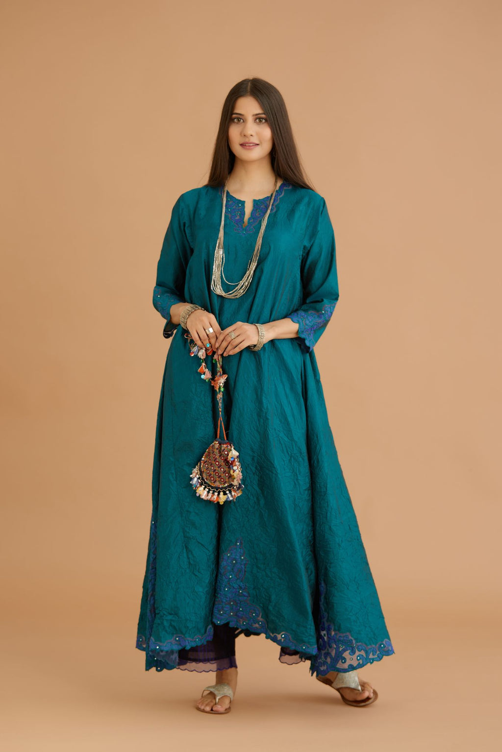Teal green hand crushed silk kurta with cutwork embroidered asymmetric hem, highlighted with hand attached mirrors, paired with blue hand crushed silk pants with hand block print fine stripes and organza fabric and embroidery detail at bottom hem.