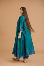Teal green hand crushed silk kurta with cutwork embroidered asymmetric hem, highlighted with hand attached mirrors, paired with blue hand crushed silk pants with hand block print fine stripes and organza fabric and embroidery detail at bottom hem.