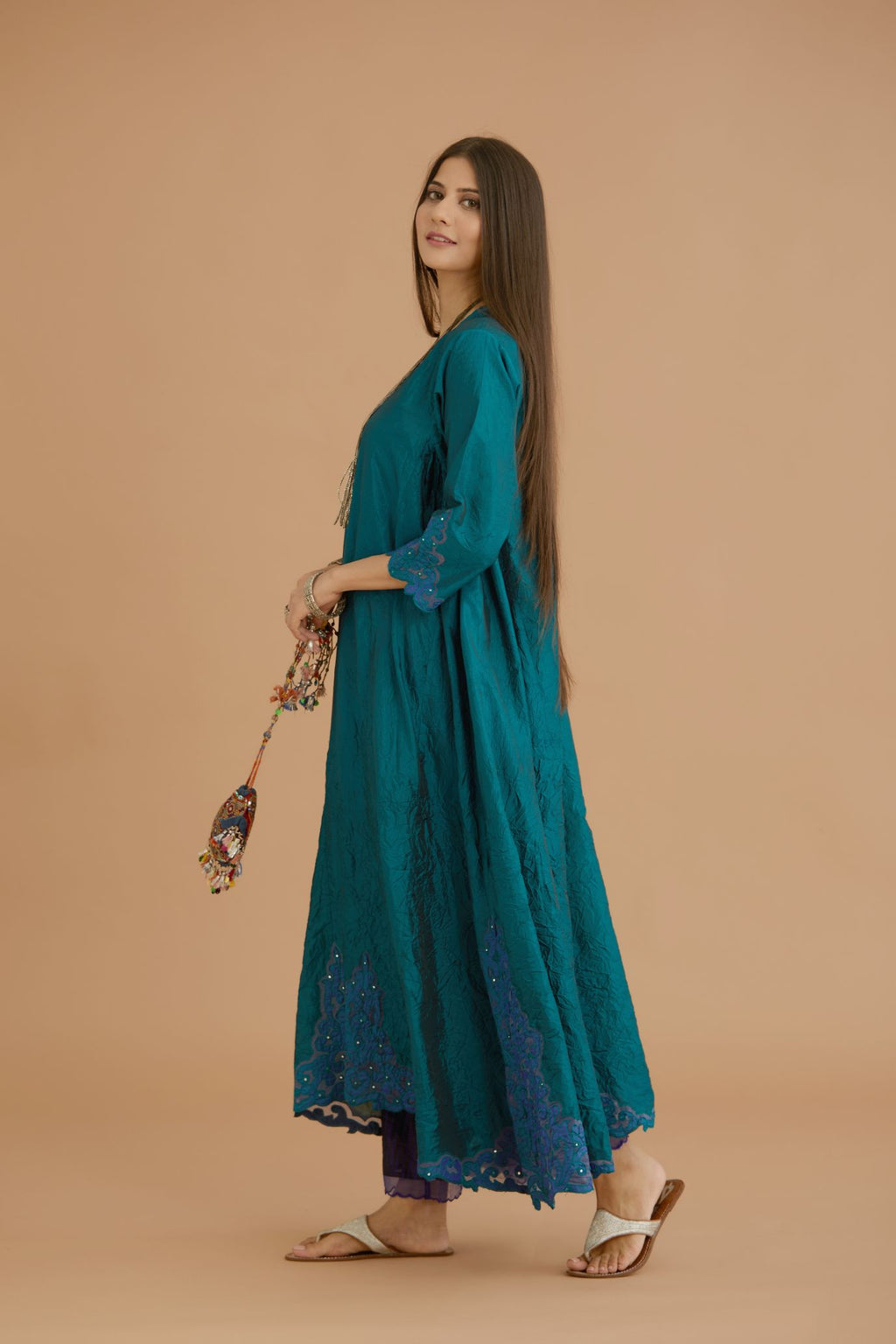 Teal green hand crushed silk kurta with cutwork embroidered asymmetric hem, highlighted with hand attached mirrors, paired with blue hand crushed silk pants with hand block print fine stripes and organza fabric and embroidery detail at bottom hem.
