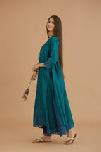 Teal green hand crushed silk kurta with cutwork embroidered asymmetric hem, highlighted with hand attached mirrors, paired with blue hand crushed silk pants with hand block print fine stripes and organza fabric and embroidery detail at bottom hem.