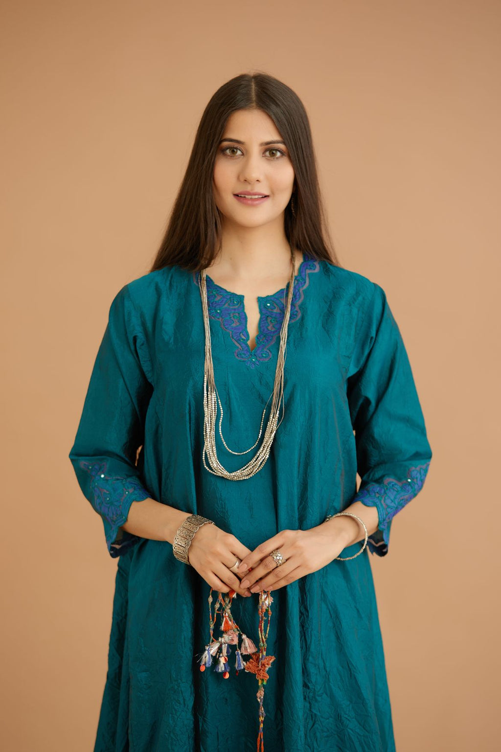 Teal green hand crushed silk kurta with cutwork embroidered asymmetric hem, highlighted with hand attached mirrors, paired with blue hand crushed silk pants with hand block print fine stripes and organza fabric and embroidery detail at bottom hem.
