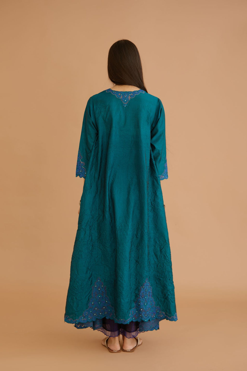 Teal green hand crushed silk kurta with cutwork embroidered asymmetric hem, highlighted with hand attached mirrors, paired with blue hand crushed silk pants with hand block print fine stripes and organza fabric and embroidery detail at bottom hem.