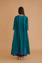 Teal green hand crushed silk kurta with cutwork embroidered asymmetric hem, highlighted with hand attached mirrors, paired with blue hand crushed silk pants with hand block print fine stripes and organza fabric and embroidery detail at bottom hem.