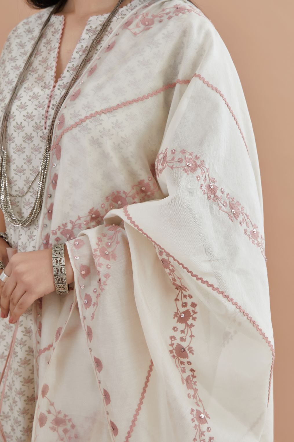 Off white silk chanderi kurta set with pink lotus hand block print, highlighted with pink thread embroidery inset and rickrack lace.