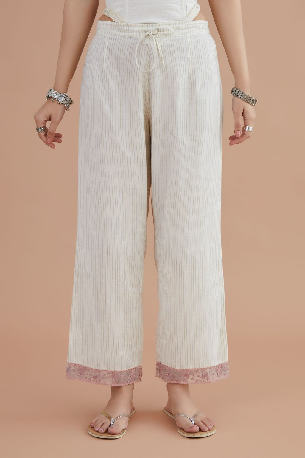 Off white straight pants detailed with pink embroidery at bottom.