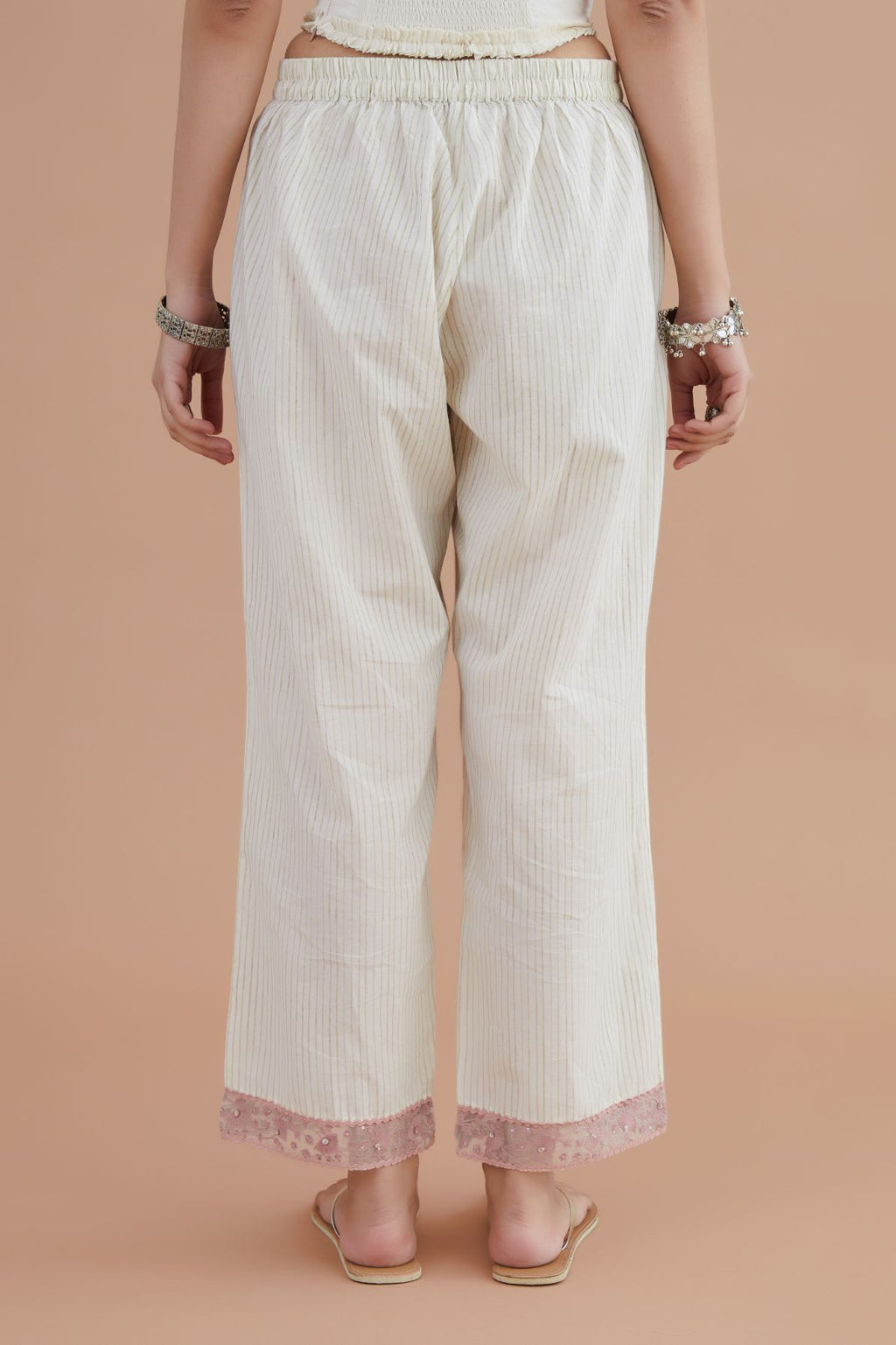 Off white straight pants detailed with pink embroidery at bottom.