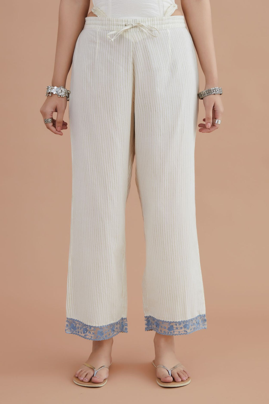 Off white straight pants detailed with blue embroidery at bottom.