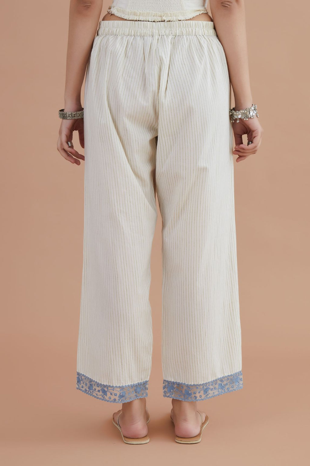 Off white straight pants detailed with blue embroidery at bottom.