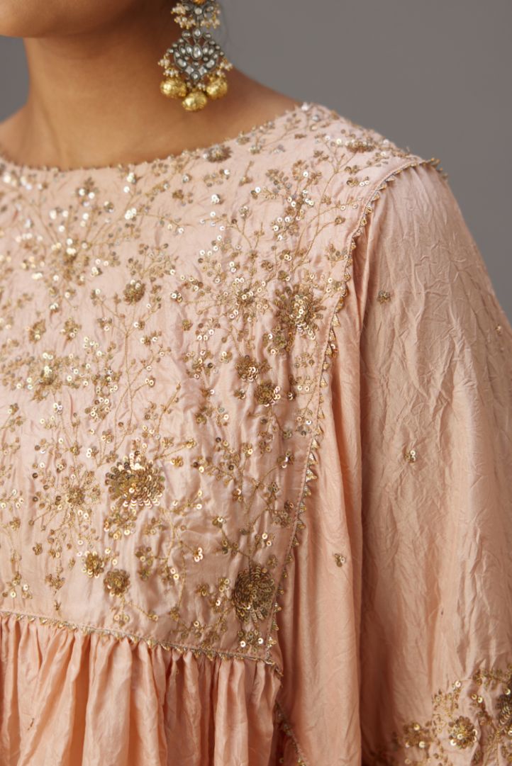 Pink solid easy fit top with golden sequins work at front and back yoke, paired with pink hand crushed silk pants with embroidered sequins border at hem.