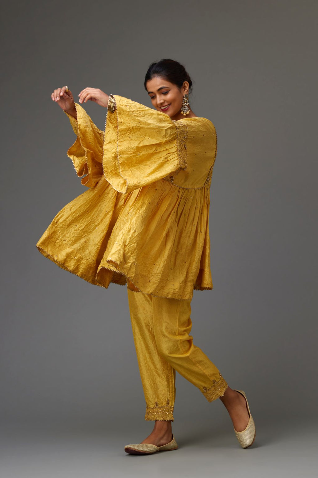 Yellow solid easy fit top with golden sequins work at front and back yoke, paired with yellow hand crushed silk pants with embroidered sequins border at hem.