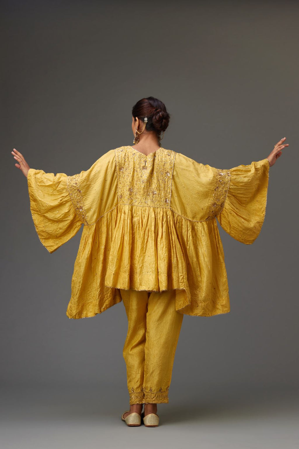 Yellow solid easy fit top with golden sequins work at front and back yoke, paired with yellow hand crushed silk pants with embroidered sequins border at hem.