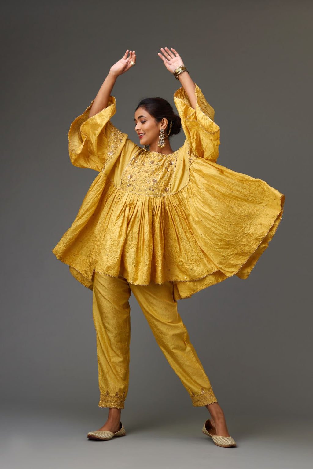 Yellow solid easy fit top with golden sequins work at front and back yoke, paired with yellow hand crushed silk pants with embroidered sequins border at hem.