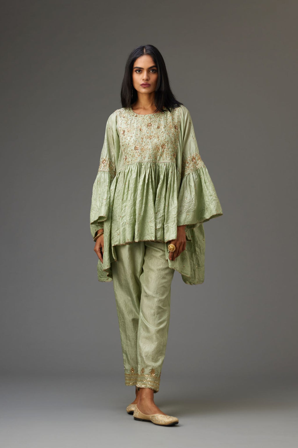 Green solid easy fit top with golden sequins work at front and back yoke, paired with green hand crushed silk pants with embroidered sequins border at hem.