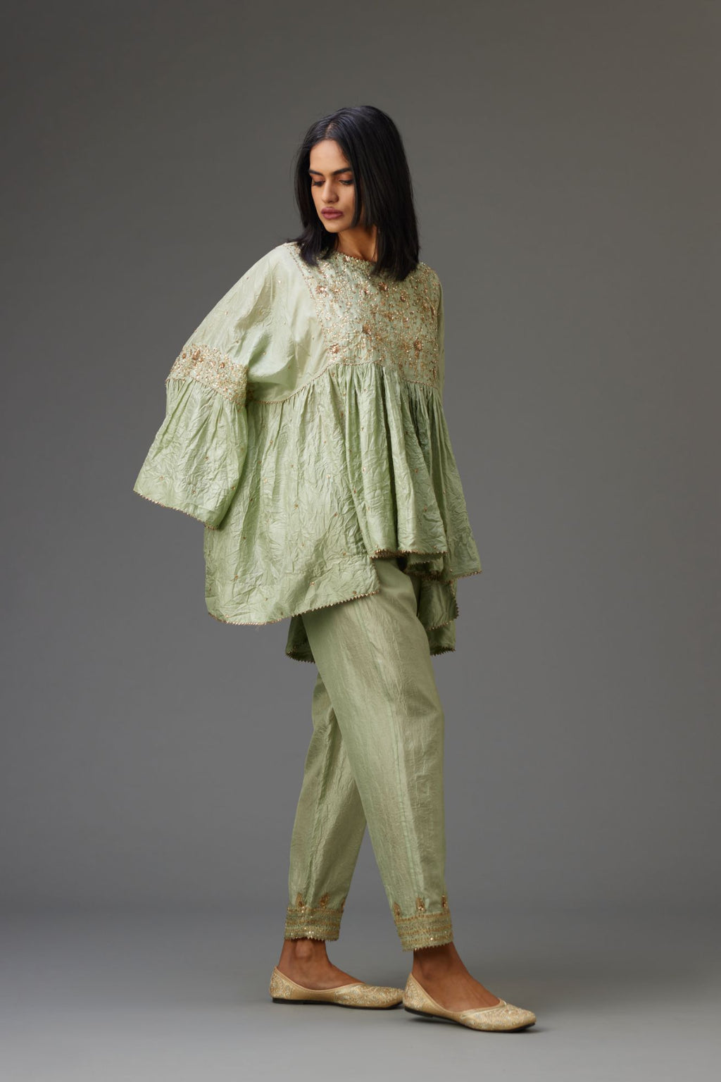 Green solid easy fit top with golden sequins work at front and back yoke, paired with green hand crushed silk pants with embroidered sequins border at hem.