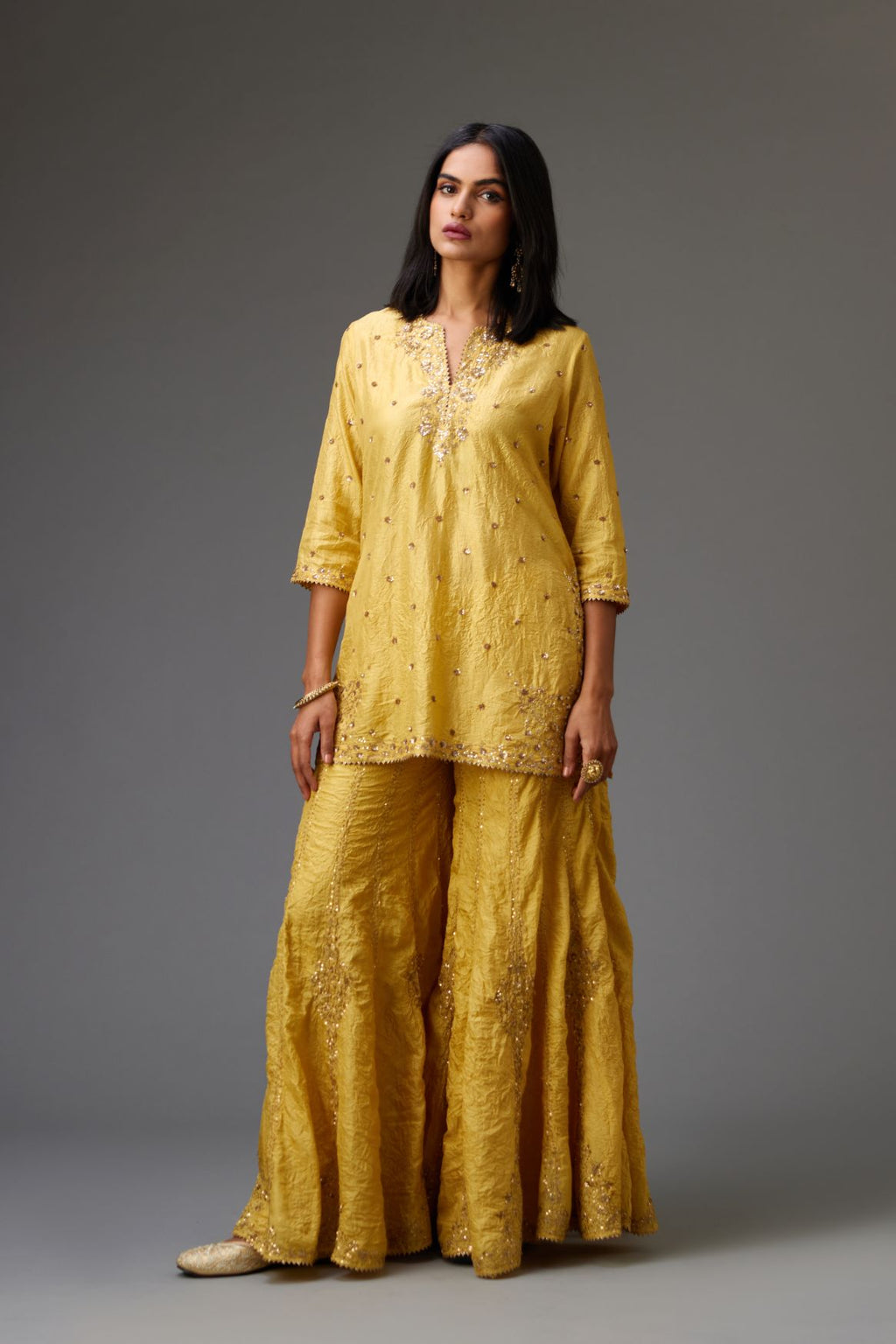 Yellow hand crushed silk short kurta set with all-over gold sequins and zari handwork, highlighted with gota lace at edges.