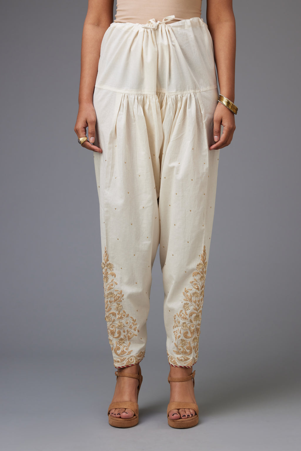Off-white cotton salwar, hem is detailed with dori, sequins and gota embroidered boota at sides.