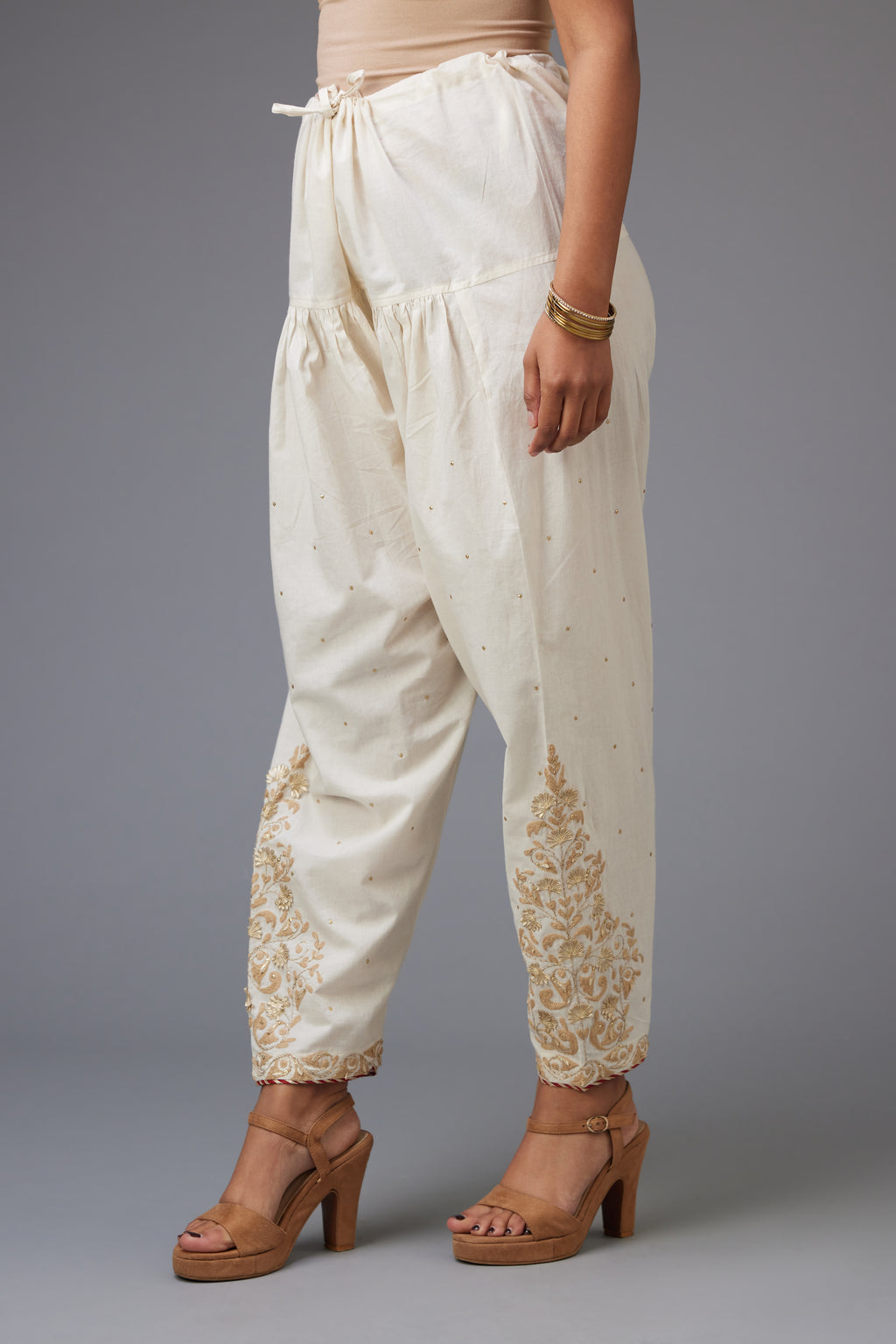 Off-white cotton salwar, hem is detailed with dori, sequins and gota embroidered boota at sides.