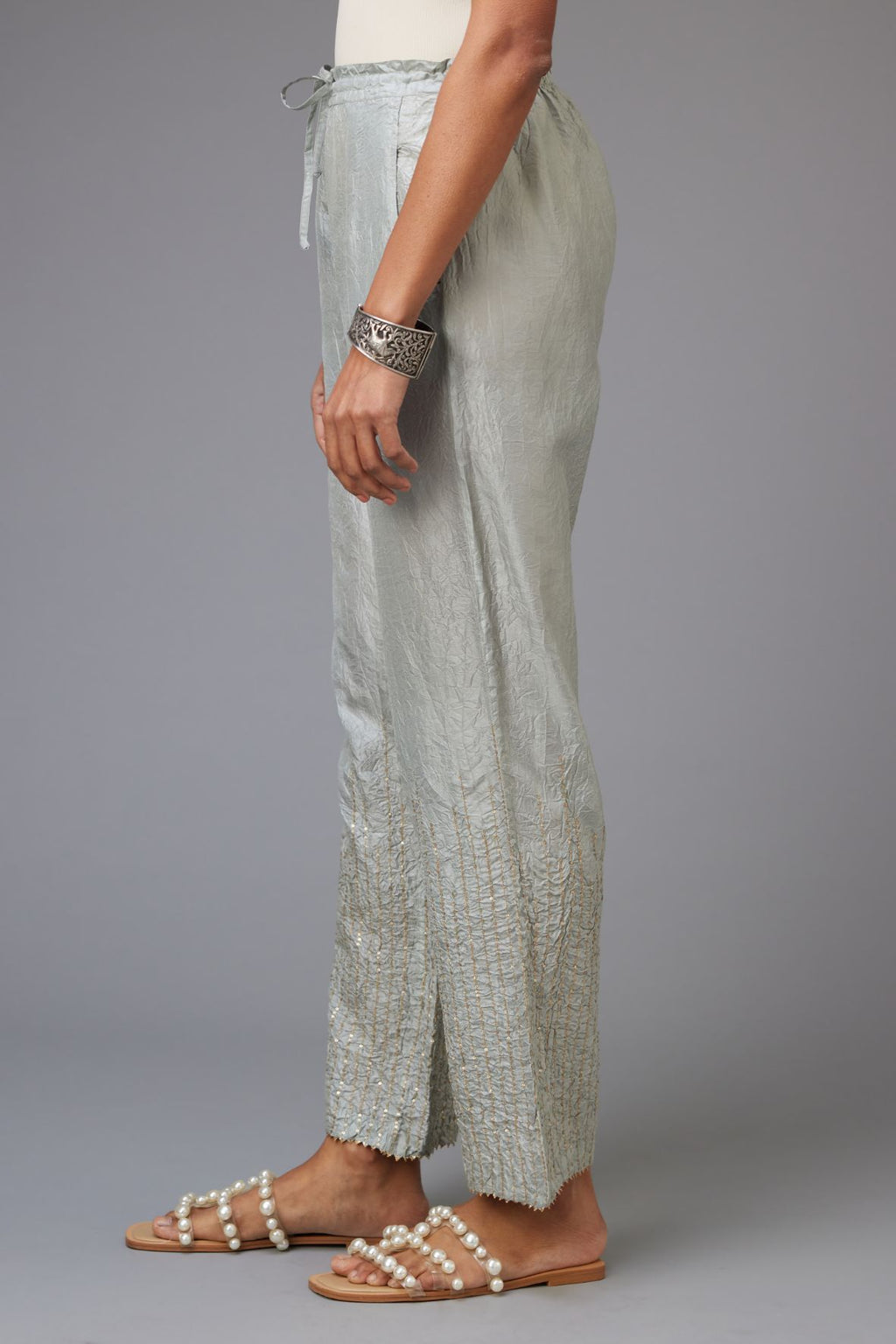 Blue hand crushed silk straight pants with golden sequin lines from calf to hem, highlighted with gota lace at edges.