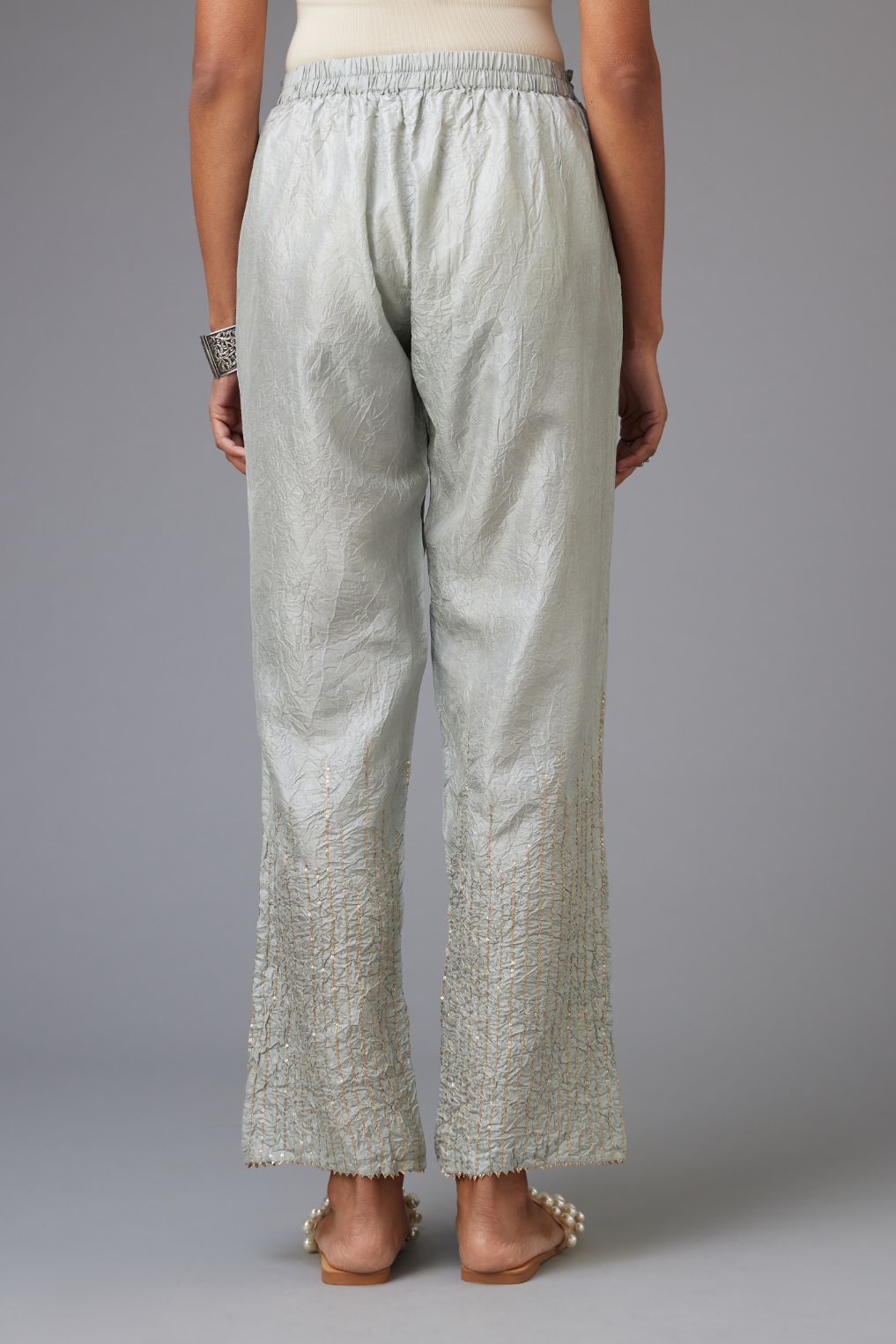 Blue hand crushed silk straight pants with golden sequin lines from calf to hem, highlighted with gota lace at edges.