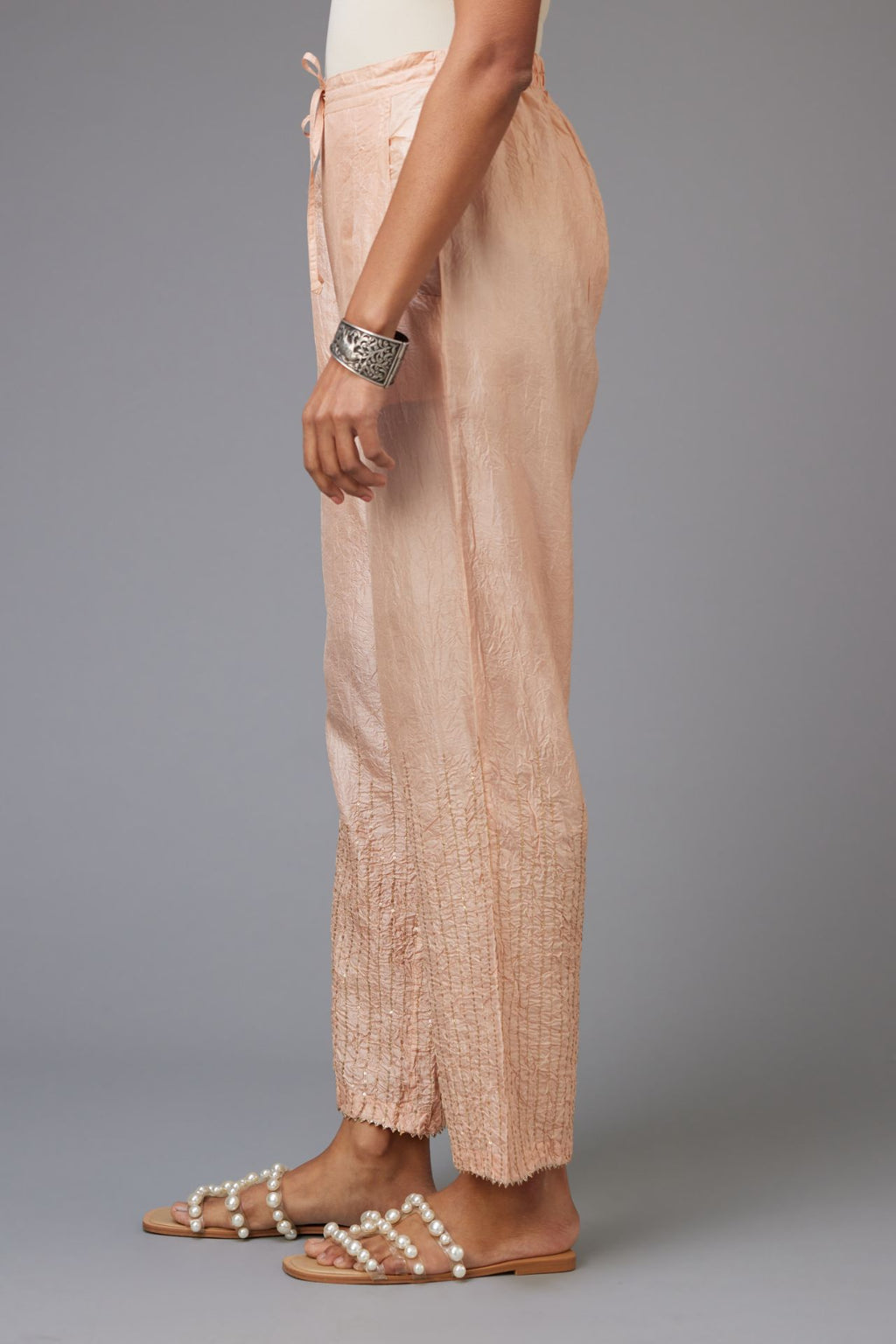 Pink hand crushed silk straight pants with golden sequin lines from calf to hem, highlighted with gota lace at edges.