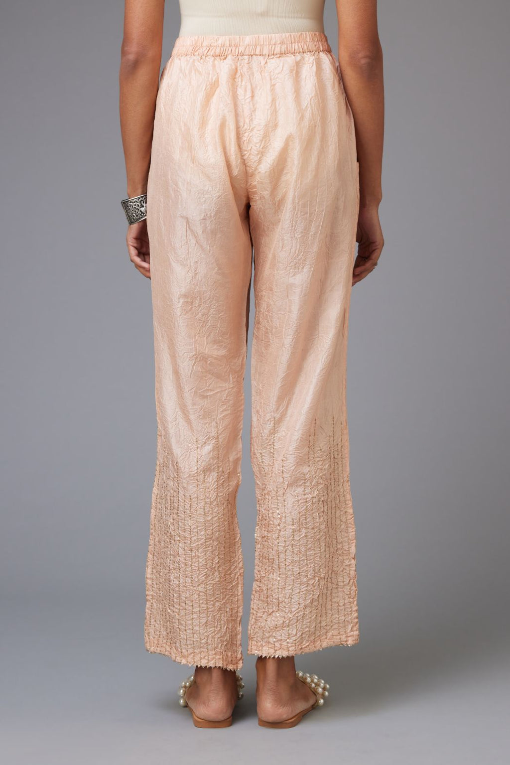 Pink hand crushed silk straight pants with golden sequin lines from calf to hem, highlighted with gota lace at edges.