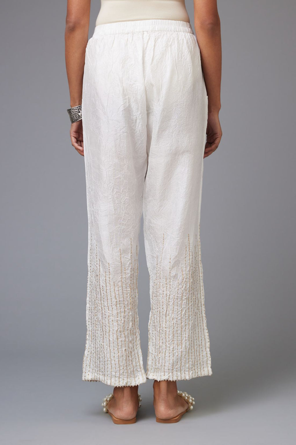 White hand crushed silk straight pants with golden sequin lines from calf to hem, highlighted with gota lace at edges.