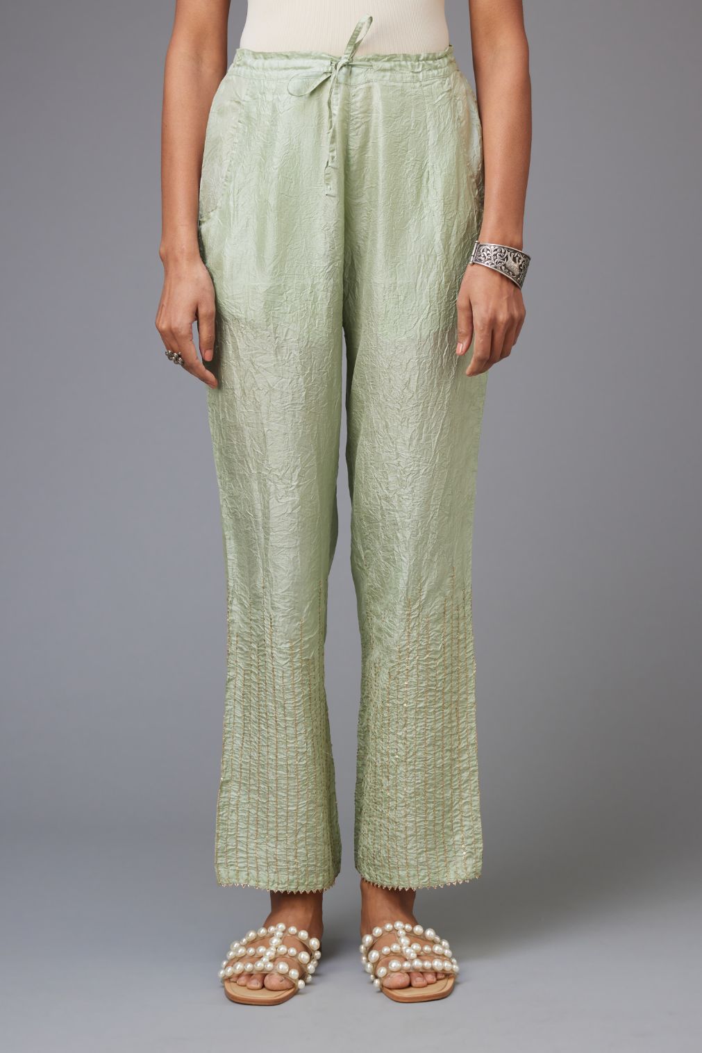 Green hand crushed silk straight pants with golden sequin lines from calf to hem, highlighted with gota lace at edges.