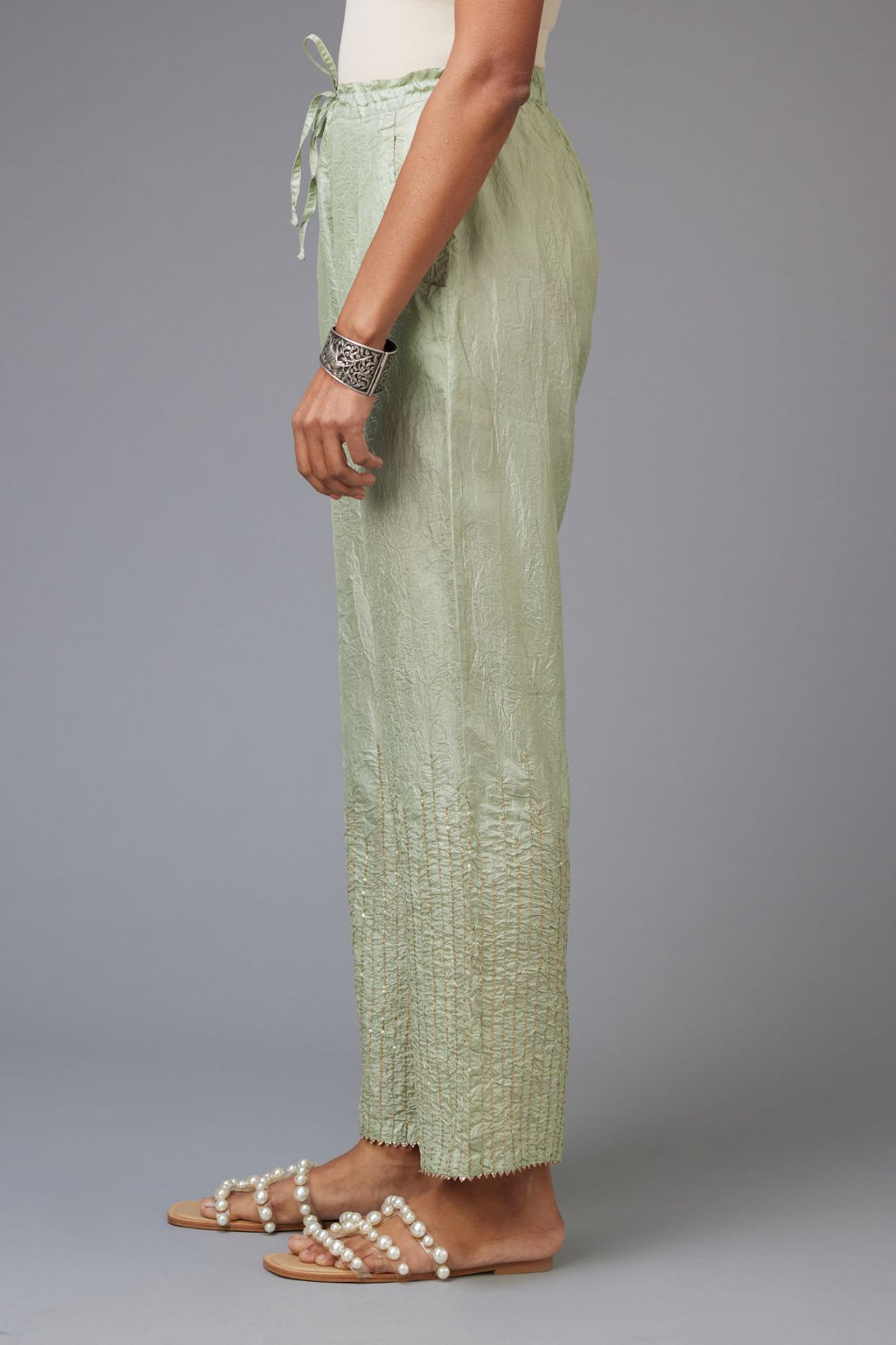 Green hand crushed silk straight pants with golden sequin lines from calf to hem, highlighted with gota lace at edges.