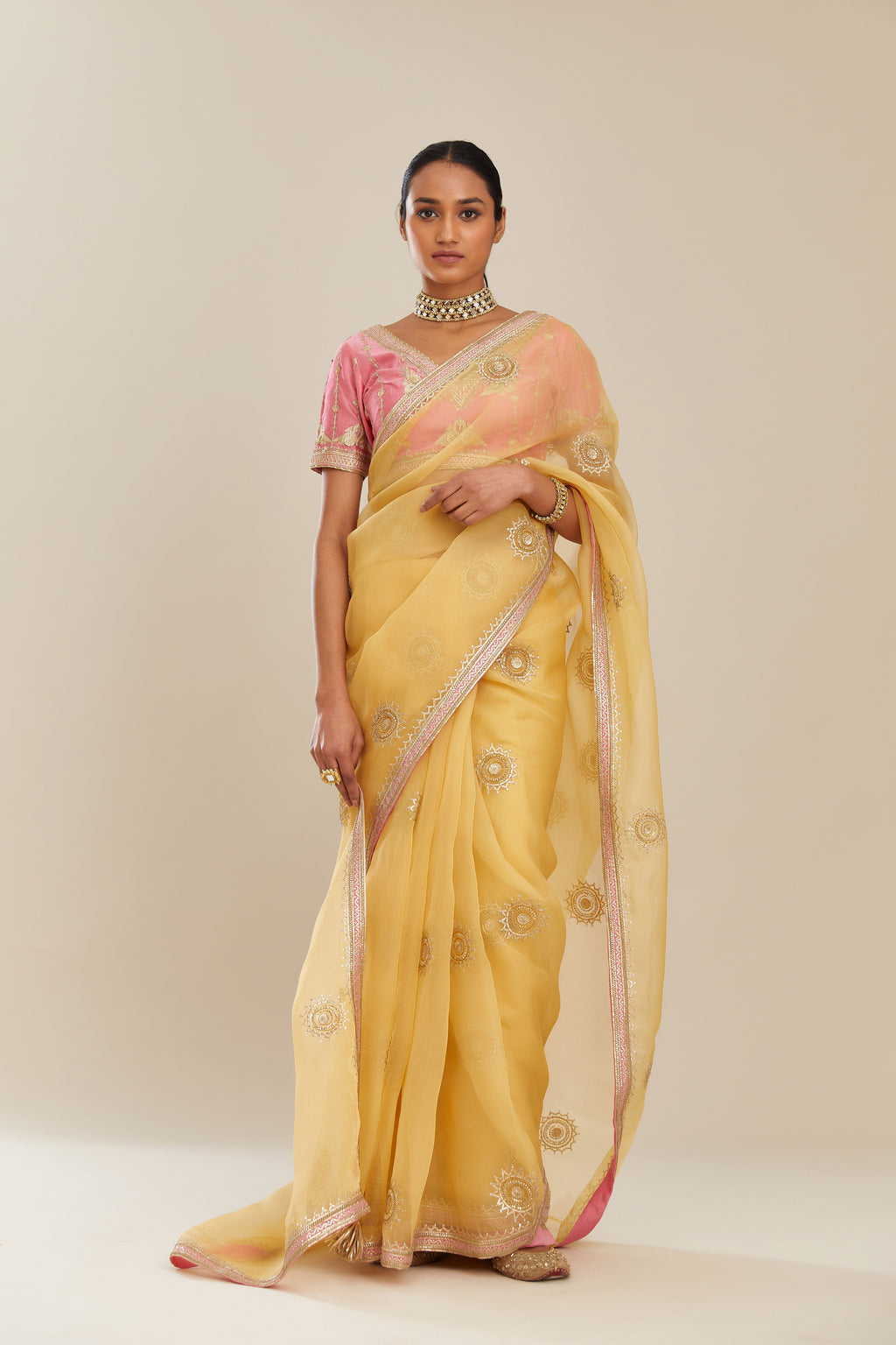Yellow silk organza saree with delicate gold gota embroidery and contrast colored border running along all edges.
