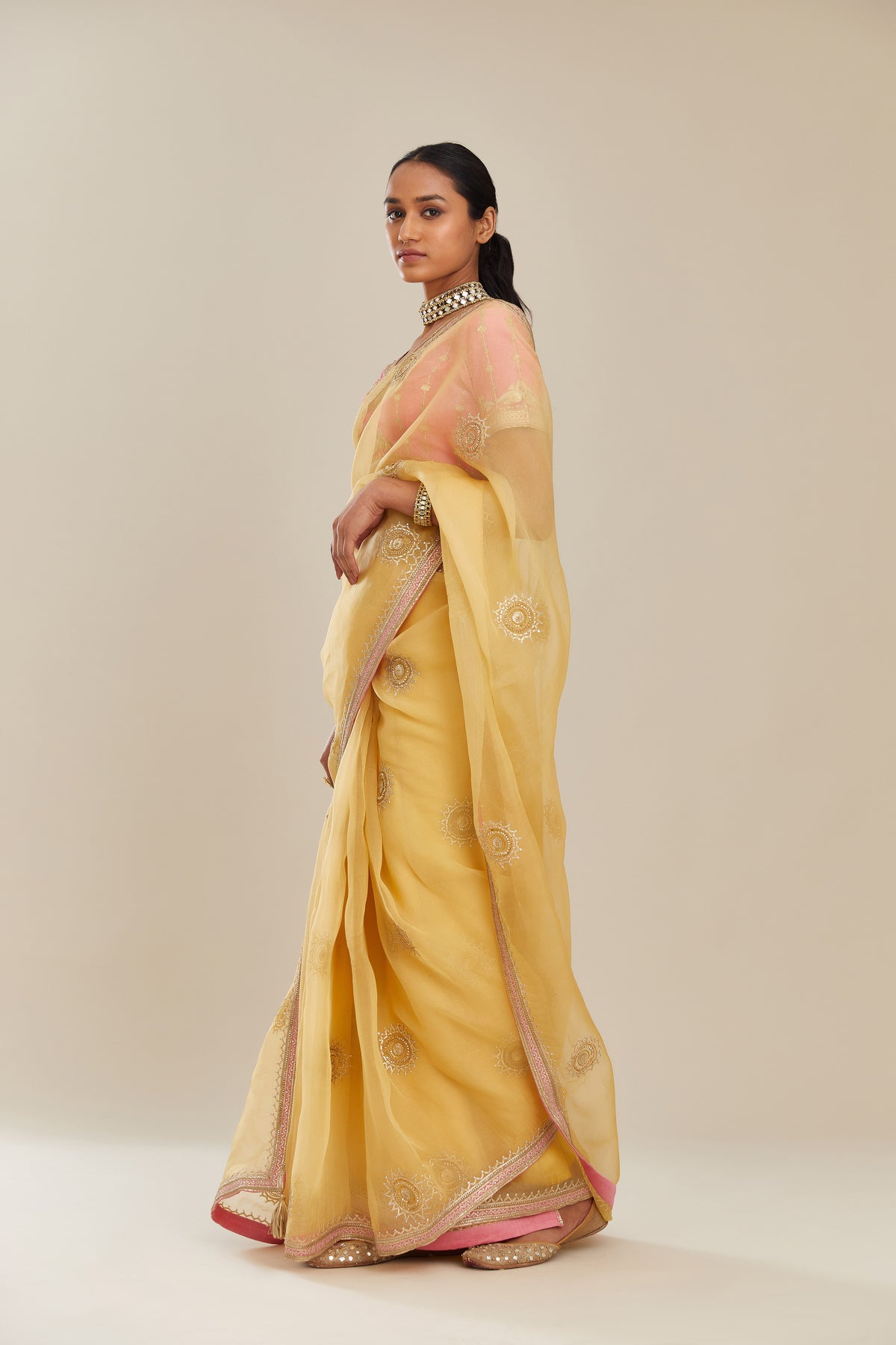 Yellow silk organza saree with delicate gold gota embroidery and contrast colored border running along all edges.