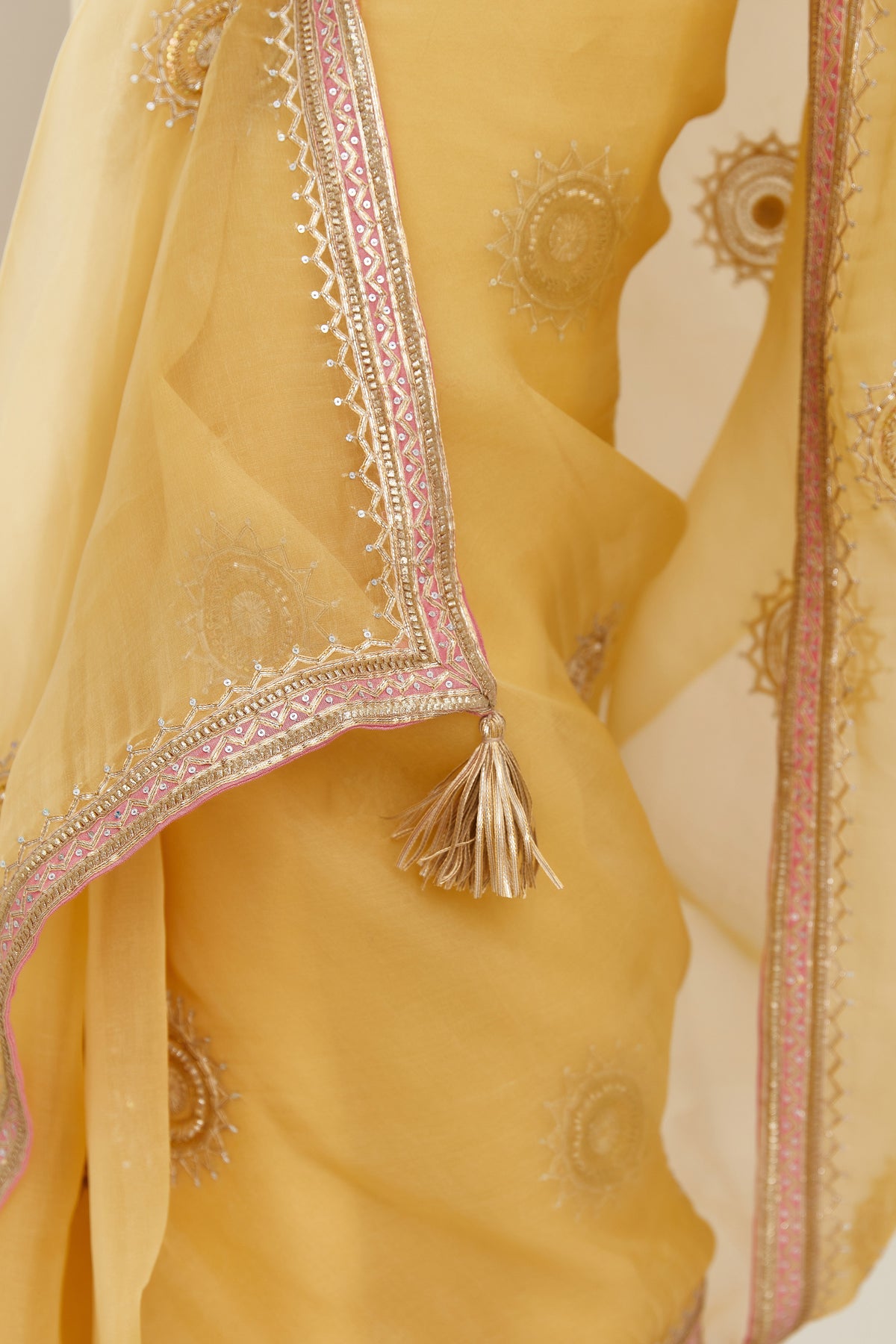Yellow silk organza saree with delicate gold gota embroidery and contrast colored border running along all edges.