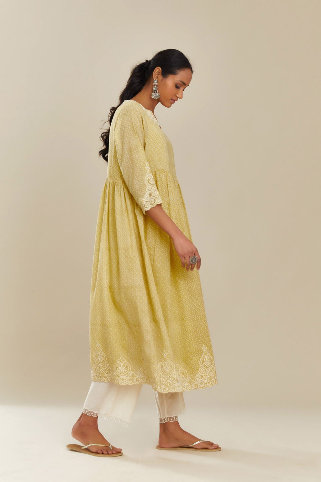 Yellow hand block over-printed cotton kurta set with wavy empire waistline,  gathers at waist and cutwork detail highlighted with sequins