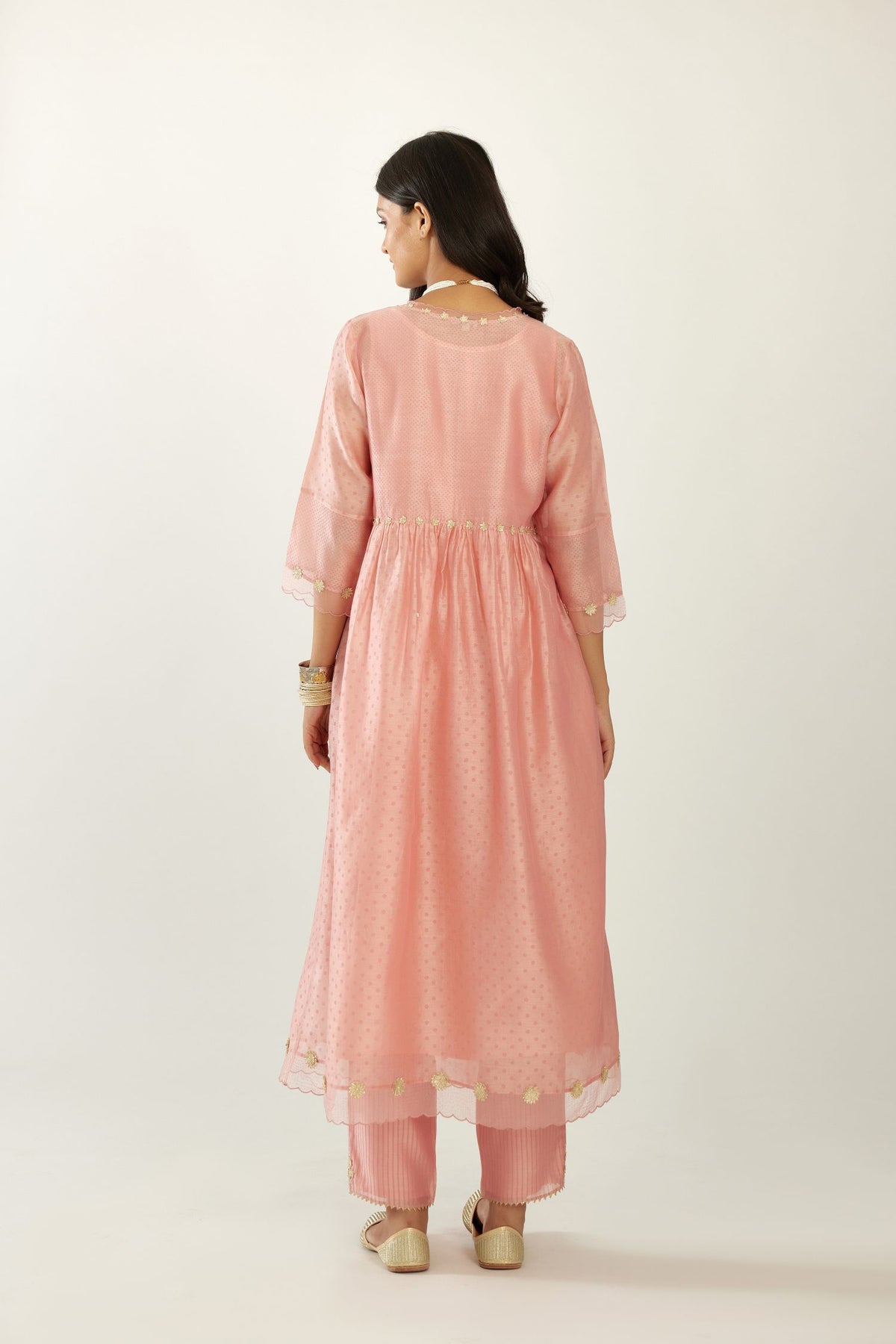 Pink hand block printed V neck gathered kurta set, highlighted with gota flower embroidery and scalloped organza at edges.